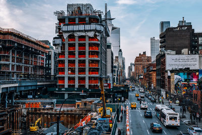 Traffic on road by buildings in city against sky