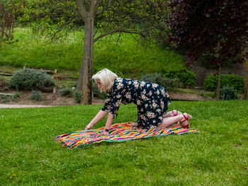 Woman putting picnic blanket on grassy field