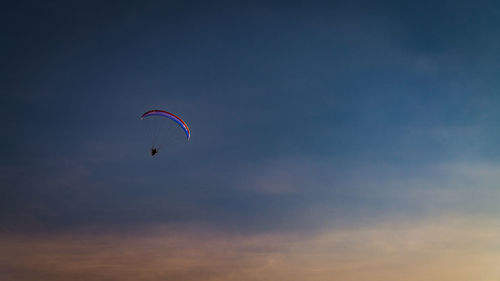 Low angle view of person paragliding against sky