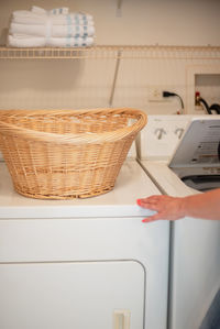 Close-up of hand holding wicker basket at home