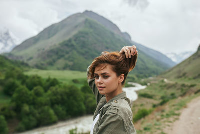 Portrait of young woman standing against mountain