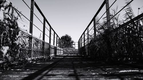 Surface level of empty footbridge against sky