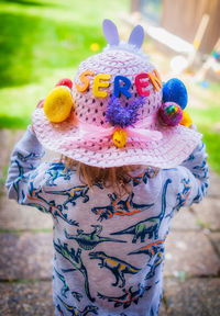 A child is facing away, wearing an easter bonnet in colour.