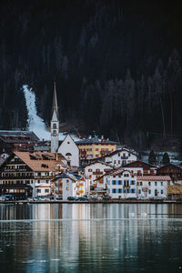 Buildings by lake in city during winter