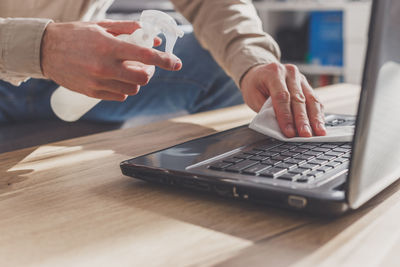 Midsection of man using mobile phone on table