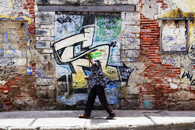 Full length of woman standing against graffiti wall