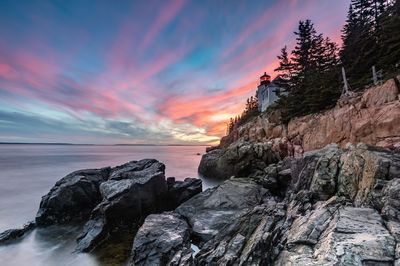 Rocks on shore against sky during sunset