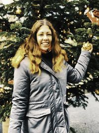 Portrait of smiling young woman standing against trees