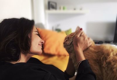 Side view of woman playing with cat at home