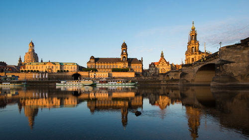 Boats moored on river by dresden frauenkirche during sunset