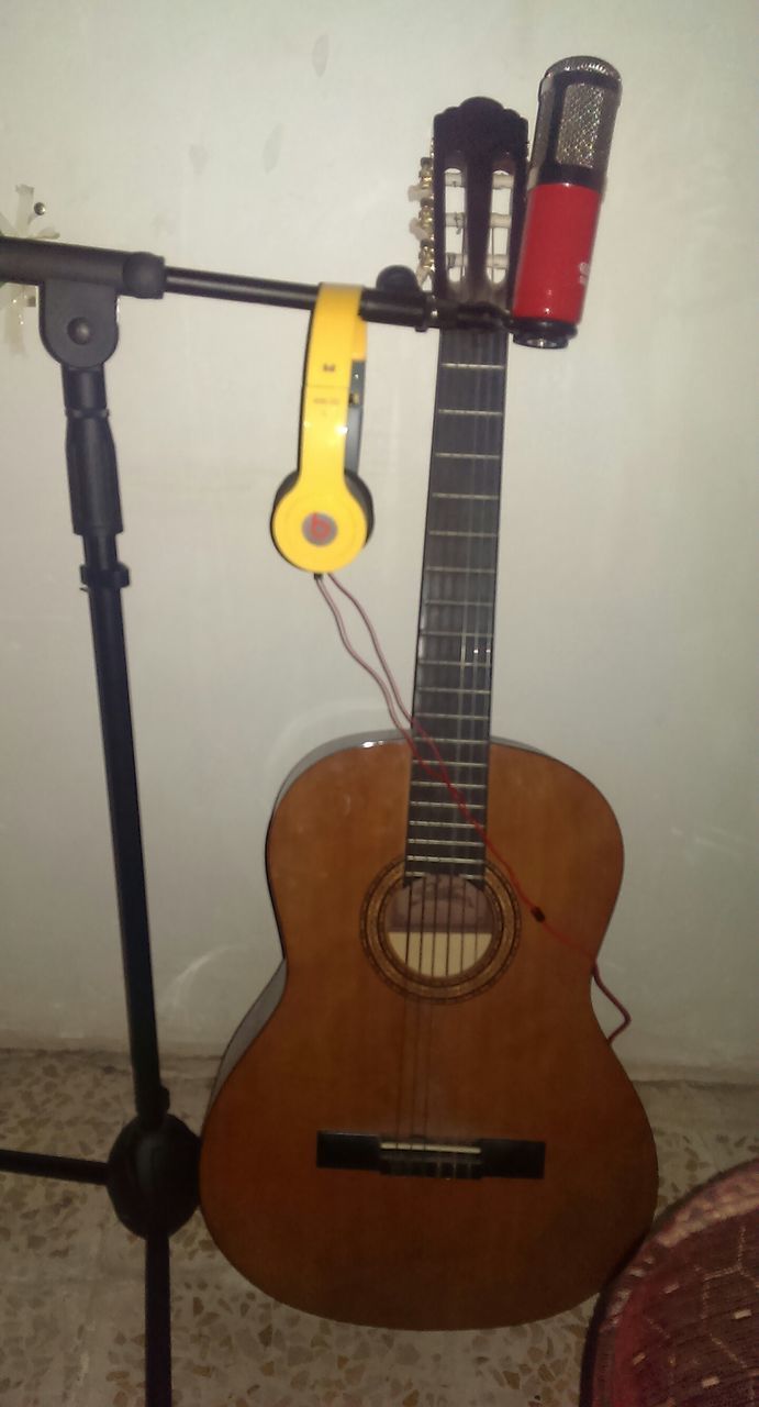 indoors, musical instrument, music, metal, still life, guitar, arts culture and entertainment, close-up, equipment, musical equipment, string instrument, single object, yellow, no people, wall - building feature, technology, absence, electricity, metallic, musical instrument string