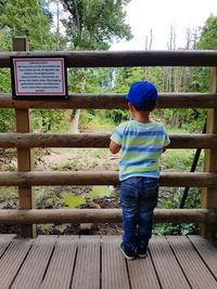 Rear view of boy standing on wood