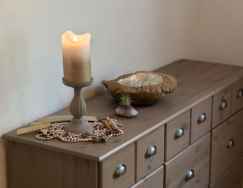 Illuminated lamp on table against wall at home