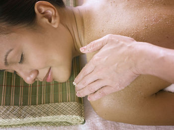 Cropped hand giving massage to woman lying on bed