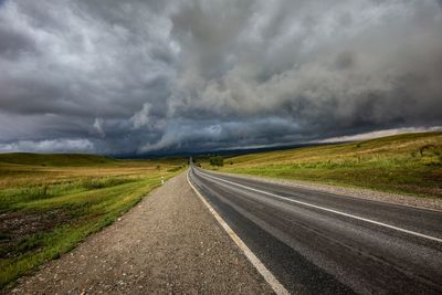 Road amidst field against sky during rainy season