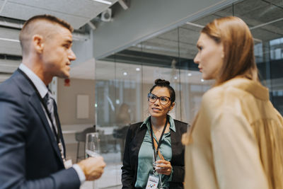 Businesswoman looking at businessman discussing strategy with colleague during seminar