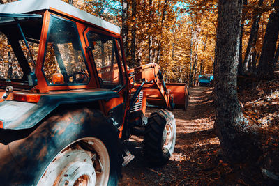 Abandoned tractor on field against trees in forest
