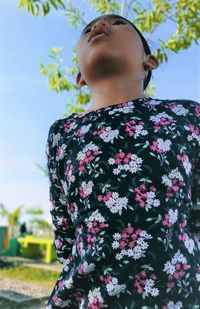 Low angle view of young woman standing by flowering plants against sky