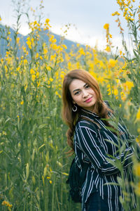 Portrait of smiling young woman standing on field