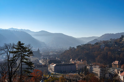 Scenic view of townscape and mountains against clear blue sky