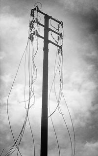 Low angle view of power lines against cloudy sky