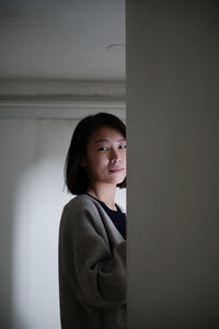 Portrait of young woman standing against wall