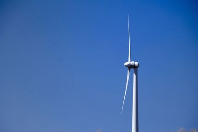 Low angle view of windmill against clear blue sky