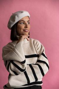 Portrait of young woman standing against yellow background