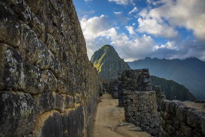 Stone wall by mountain against sky