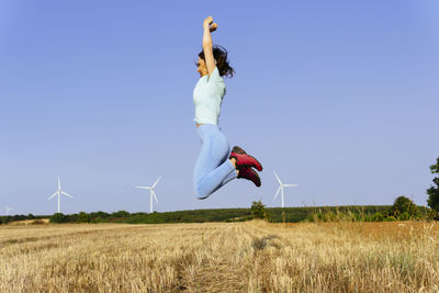 Man jumping on field against clear sky