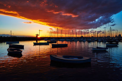 Sailboats moored in marina at sunset