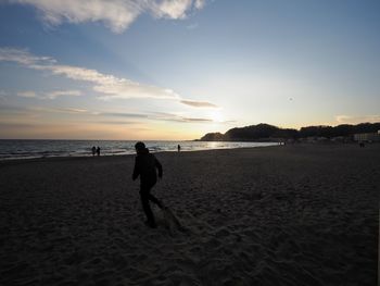Silhouette man on beach against sky during sunset