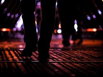 Low section of people walking on illuminated street