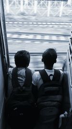 Teenage boys with bags sitting at door of train