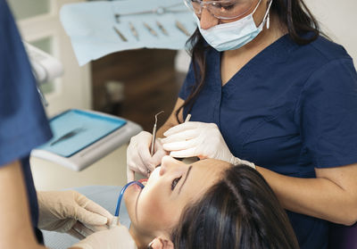 Cropped image of dentists examining woman teeth at hospital