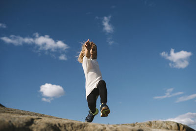 Low angle view of girl jumping on rocks
