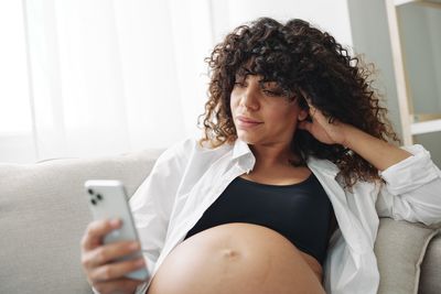 Portrait of smiling young woman using mobile phone at home