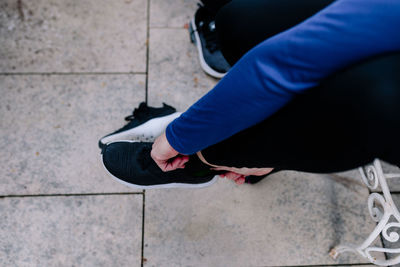 Low section of woman wearing shoes on footpath