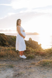 Young woman standing on field against sky