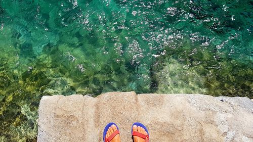 Low section of person wearing canvas shoes on swimming pool