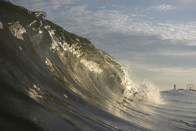 Waves splashing on shore against sky