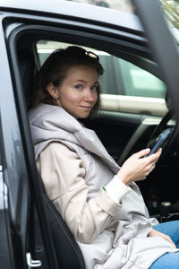 Portrait of smiling young woman sitting in car