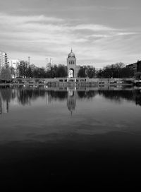 Reflection of trees in lake against sky in city