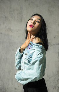 Portrait of a beautiful young woman standing against wall