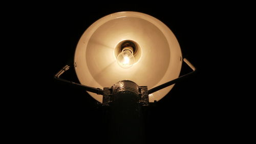 Low angle view of illuminated light bulb against black background