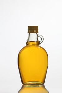 Close-up of yellow syrup in bottle against white background