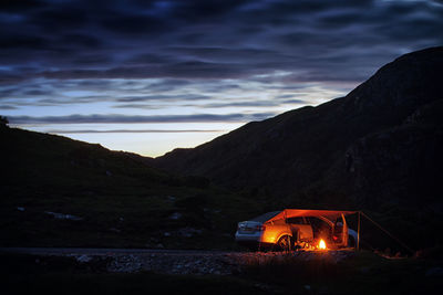 Illuminated car on mountain against sky during sunset