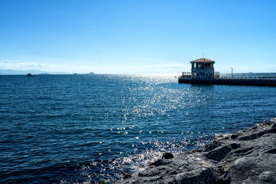 Lighthouse by sea against blue sky