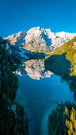 Scenic view of lake by mountains against clear blue sky