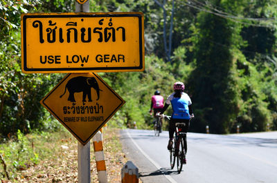 Rear view of man riding bicycle on road